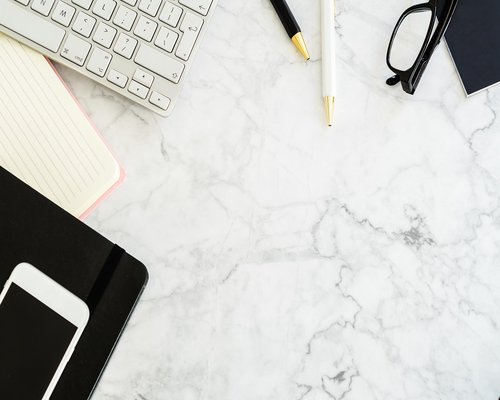 A quiet desk setup with a notebook and plants indicating an editorial workspace